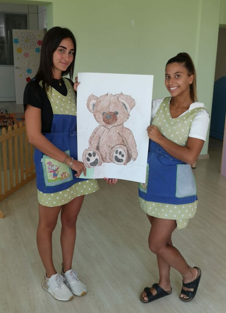 due ragazze sorridenti mostrano dipinto di un orsacchiotto