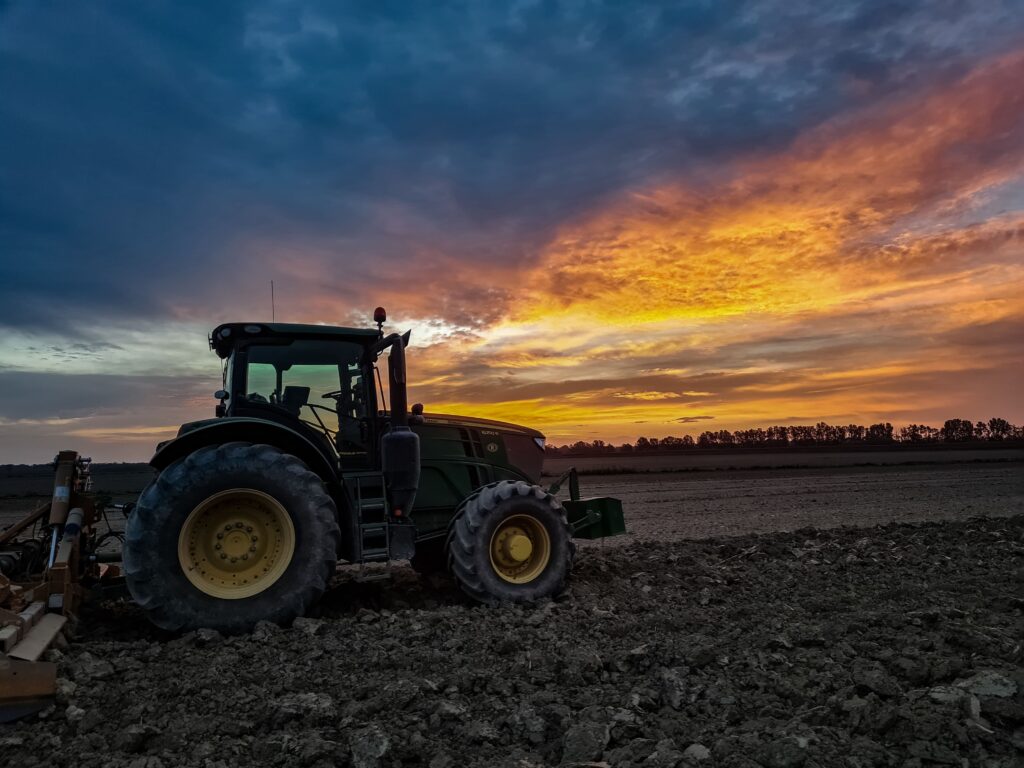 trattore al lavoro in un campo agricolo al tramonto