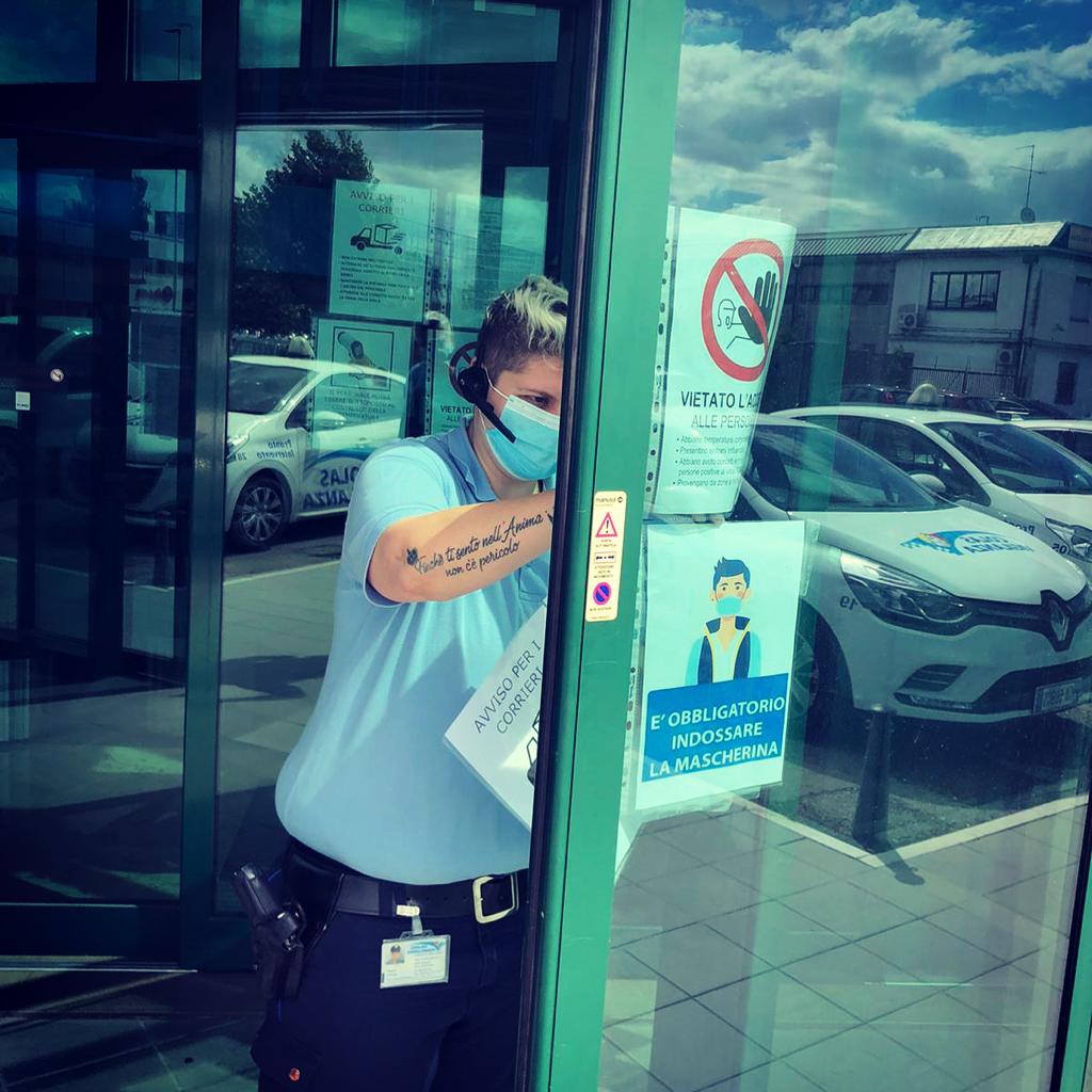 Una guardia giurata affigge un cartello sulla vetrata di un edificio